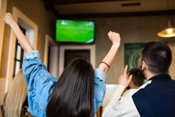 A group of friends are watching a soccer game on TV at a bar